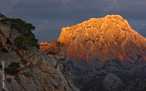 Mountain in orange light. Cliff top Sokol in sunset light against the background of thunderclouds. Crimea  Novy Svet.
