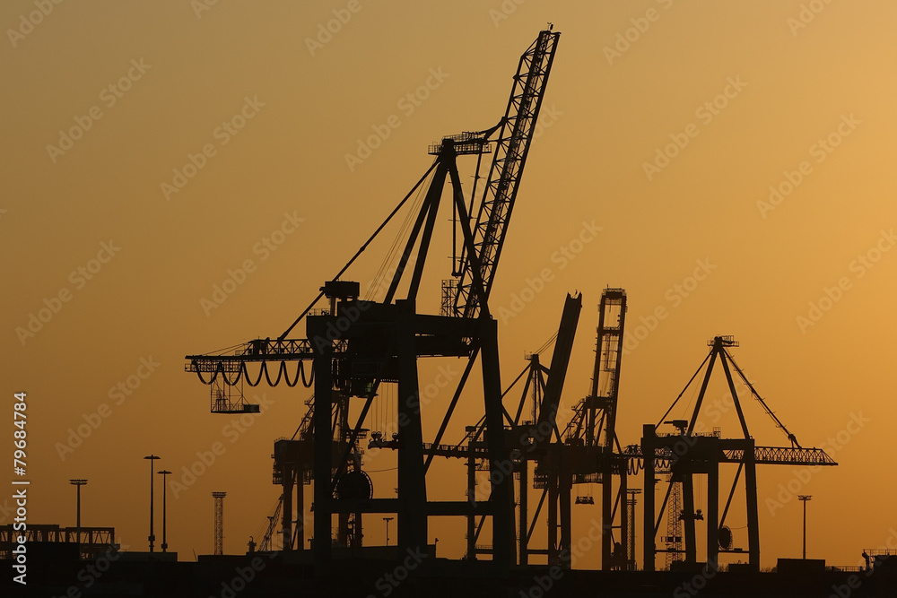 Silhouettes of shipyard cranes on the sunset sky