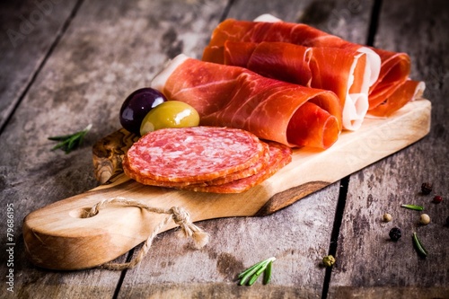 slices of prosciutto with salami, olives and rosemary