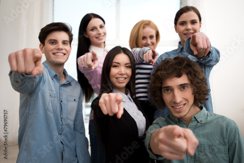 Business team smiling and pointing at camera