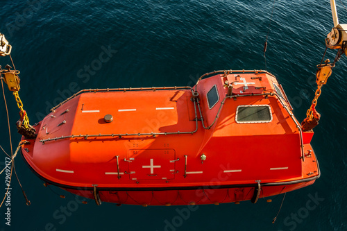 Photography Lowered orange lifeboat with a sea background