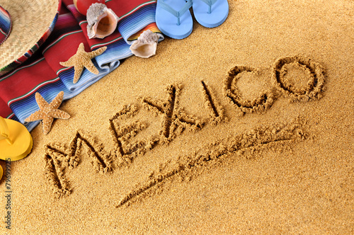 Mexico beach writing word written in sand with traditional rug or blanket and sombrero photo