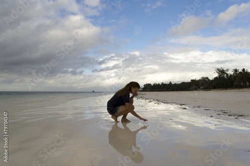 Young woman sitting on beach with reflective sand photo
