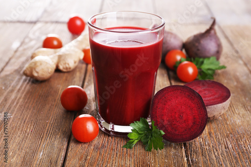 Glass of beet juice with vegetables on wooden table close up