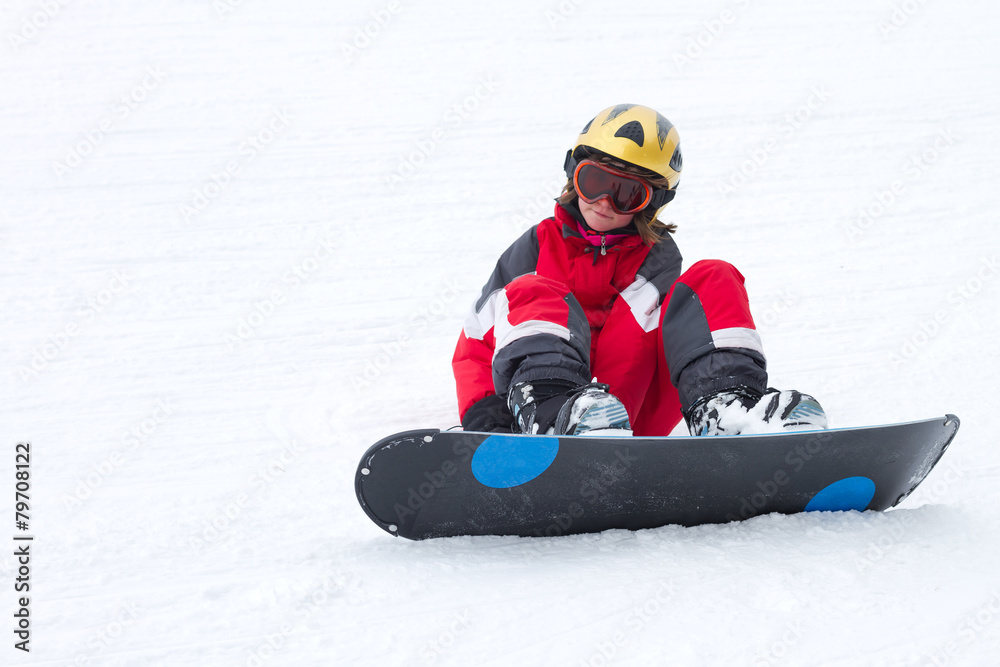 Little girl on a snowboard sitting and resting on snow