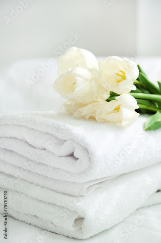White beautiful tulips on fresh towels in hotel, close up