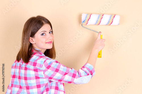Beautiful woman paints wall in room