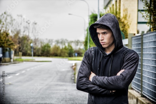 Handsome young man in black hoodie sweater standing outdoor © theartofphoto