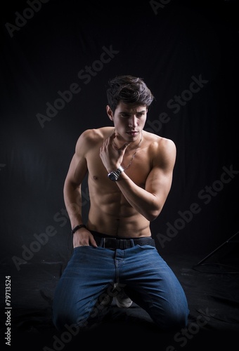 Foto Handsome muscular shirtless young man kneeling down on the floor