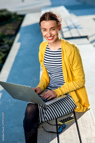 Woman with laptop and phone outdoors