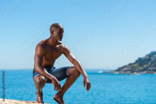 Topless African black man crouching with short jeans