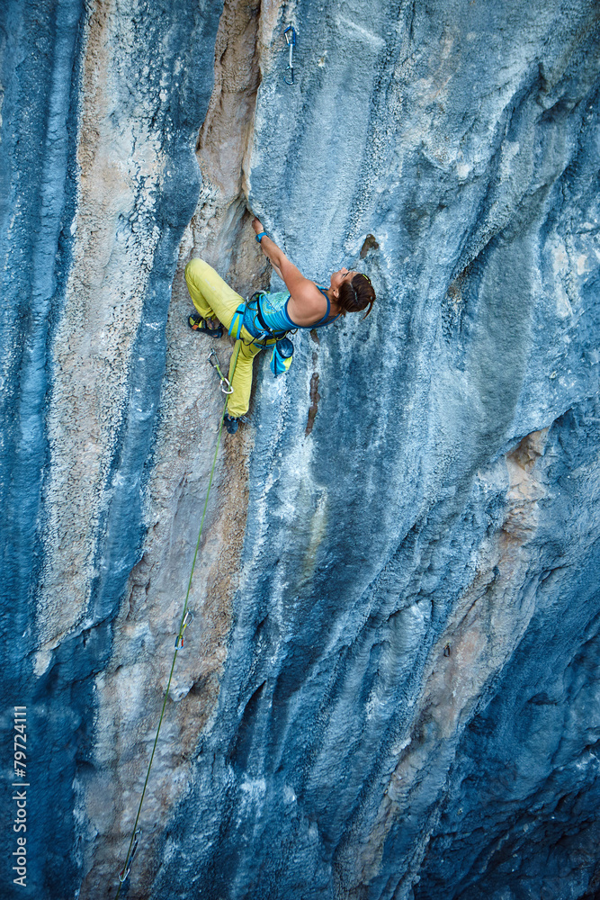 Fototapeta premium Rock climber climbing up a cliff