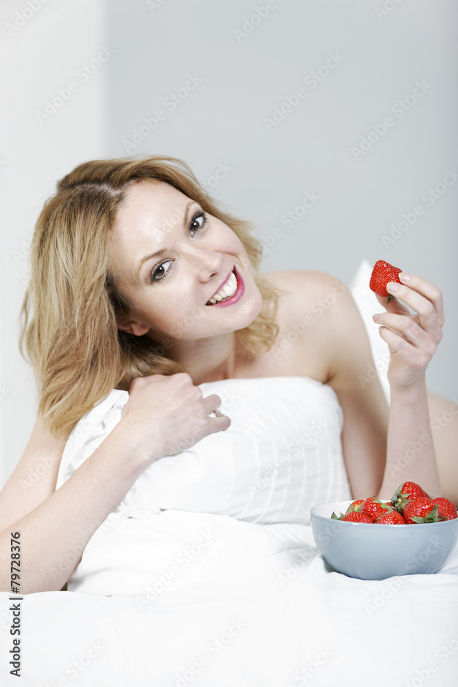 Woman lying on her bed with strawberries Woman lying on her bed with strawberries