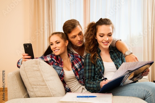Three young students preparing for exams in apartment interior