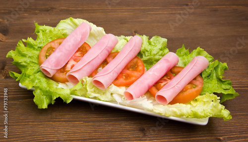 Ham rolled on salad on wooden table