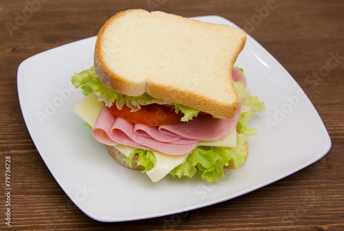 Slices of bread with ham and salad on wooden table