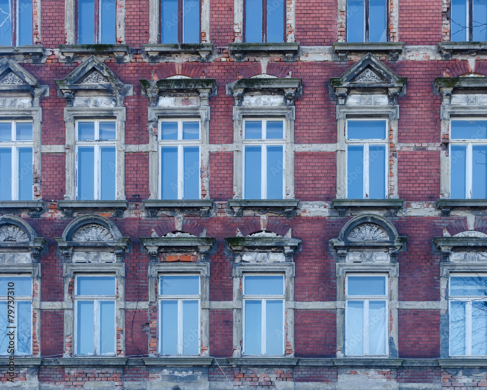 Fototapeta premium facade of an old building with windows reflecting the blue sky