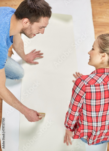 close up of couple smearing wallpaper with glue