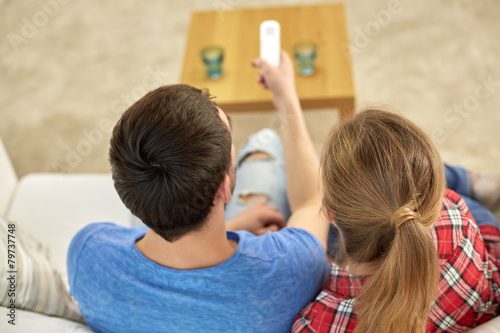 close up of couple with remote watching tv at home
