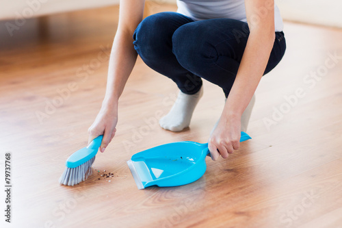 close up of woman with brush and dustpan sweeping photo