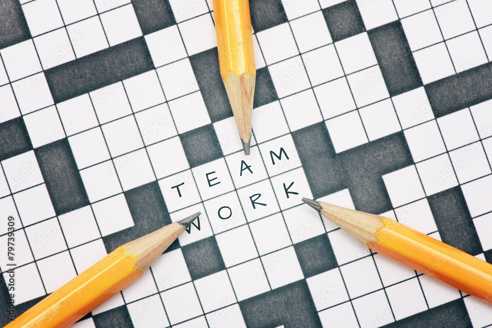 Crossword puzzle and pencils pointing to the word teamwork. ภาพถ่าย