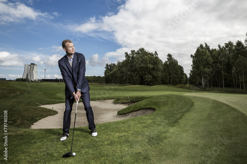 Young handsome business man playing golf outdoors