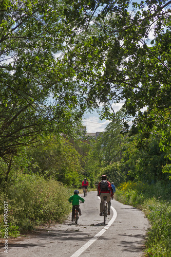 Ciclistas, niño y adultos, en Carril Bici y entre arboles
