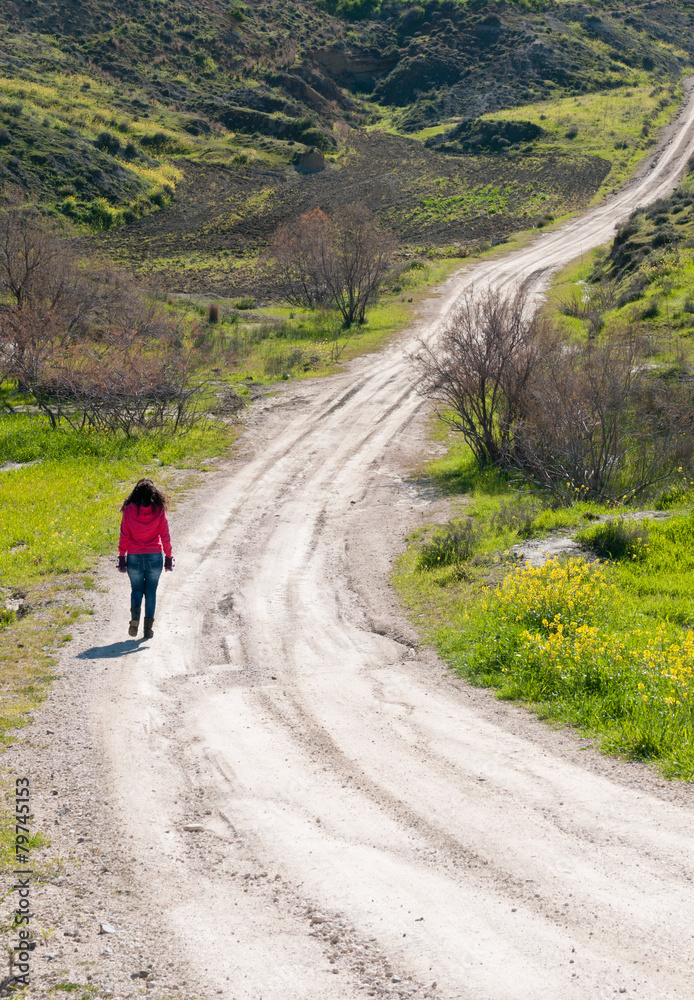 Teenage girl walking in a country dirt road