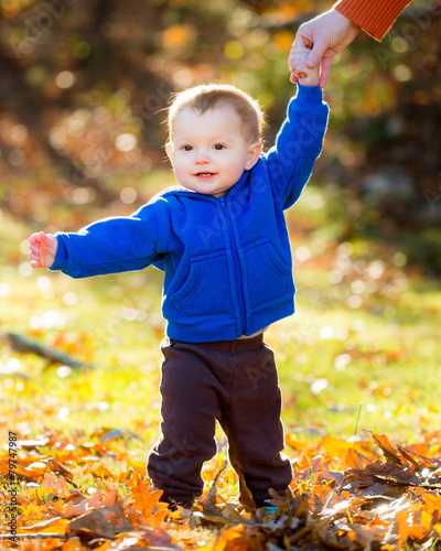 Baby practicing walking outdoors on fall day