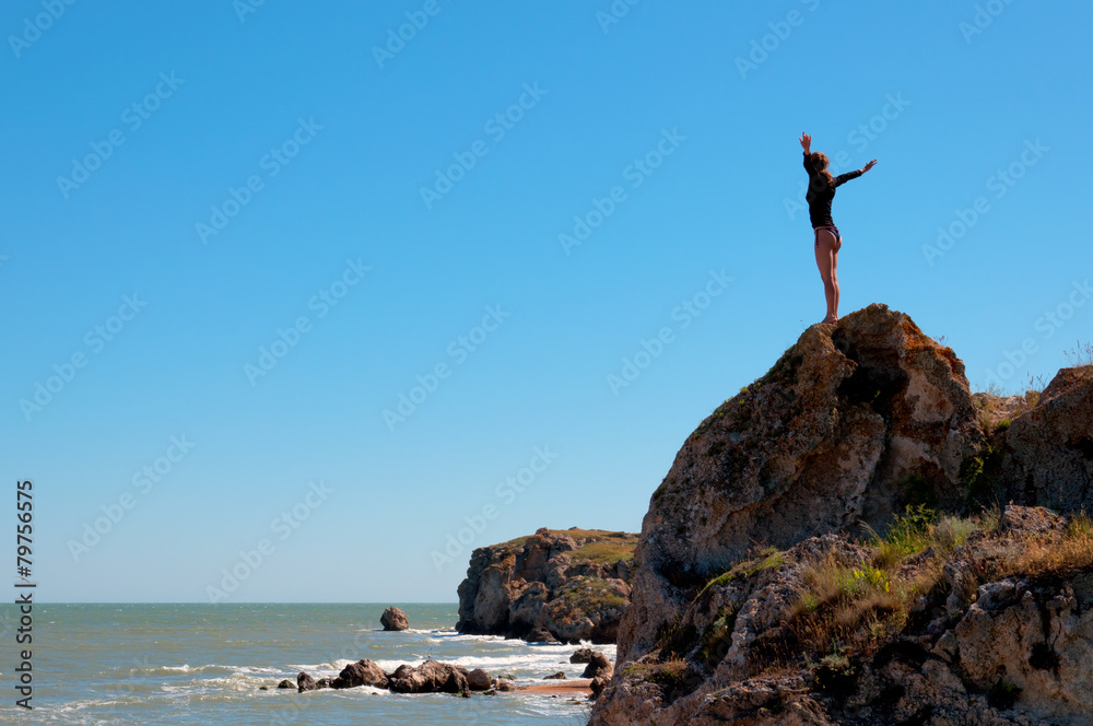 Woman standing on a natural coastal rock high up.