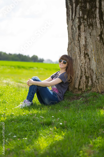 Smiling brunette woman leaning on tree