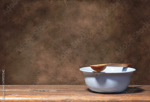 Blue bowl and wooden spoon on brown grunge background