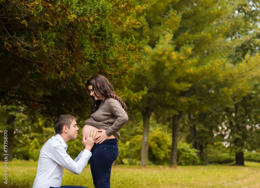Happy and young pregnant couple hugging in nature Happy and young pregnant couple hugging in nature