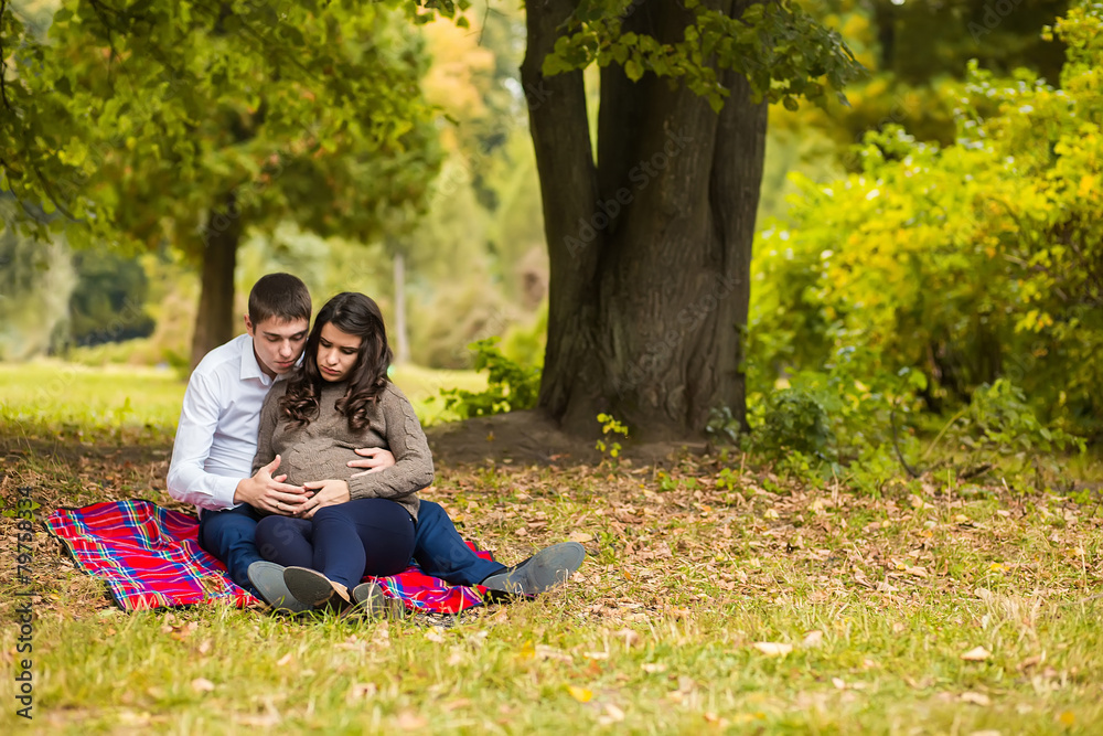 Happy and young pregnant couple hugging in nature Happy and young pregnant couple hugging in nature