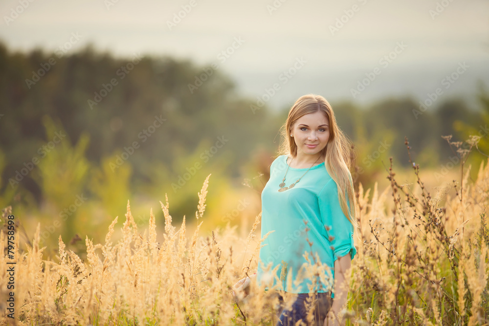Young pretty woman with long hair standing on a field with sunri Young pretty woman with long hair standing on a field with sunri