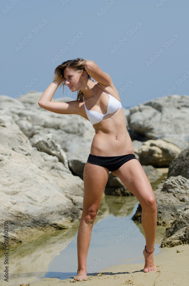 Model between sea rocks wearing a black and white bikini