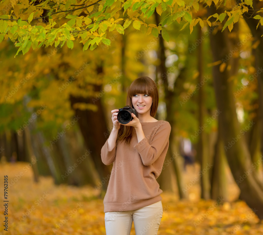 Young woman photographer in yellow autumn park