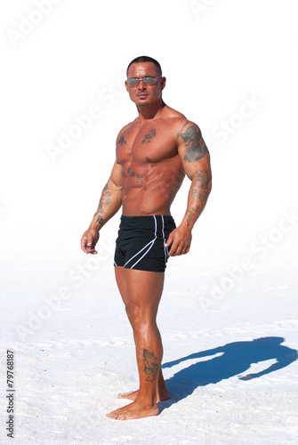 Muscular man on white background with sand
