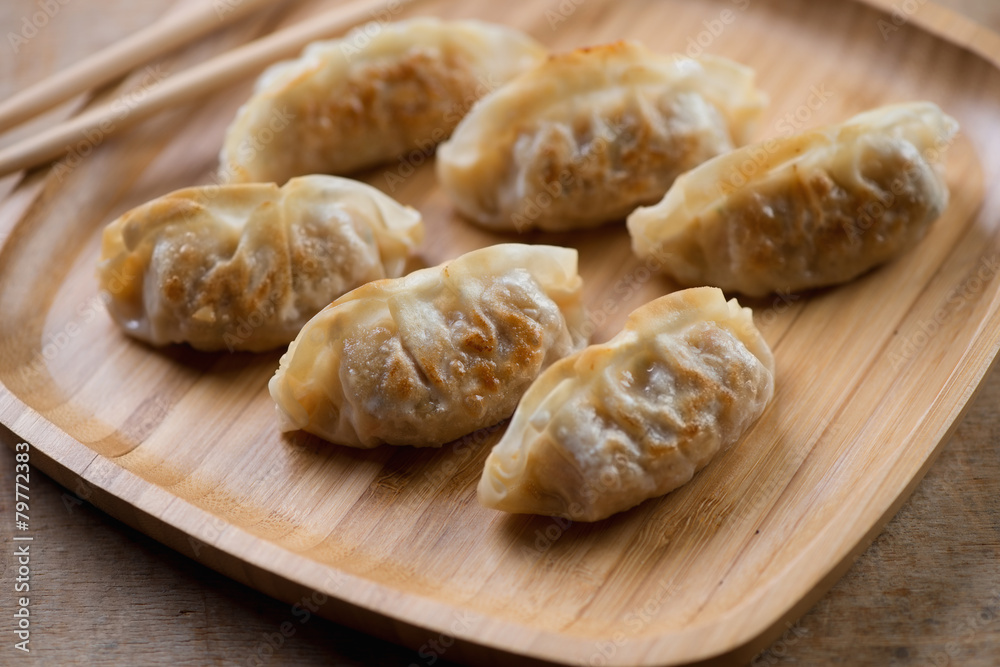 Close-up of pan fried gyoza on a bamboo tray, horizontal shot Close-up of pan fried gyoza on a bamboo tray, horizontal shot