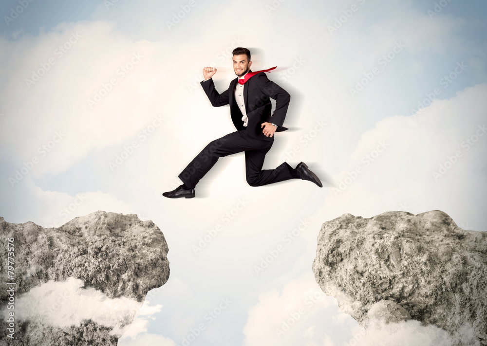 Happy business man jumping over a cliff Happy business man jumping over a cliff