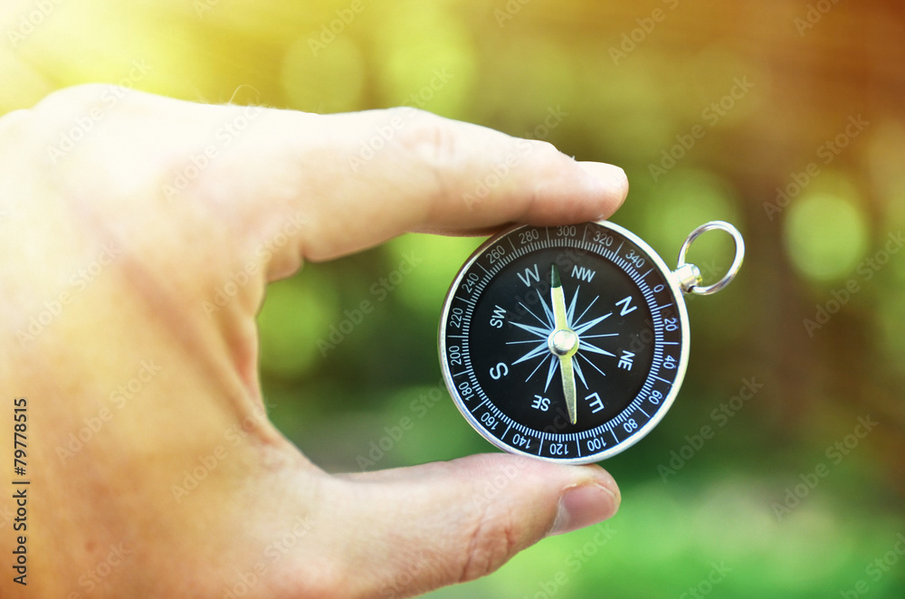 Compass in the hand against against wood Compass in the hand against against wood