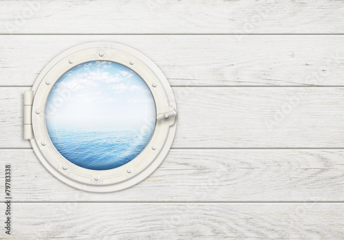 ship window or porthole on white wooden wall with sea or ocean photo