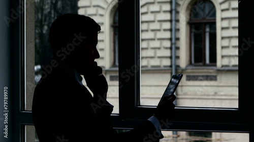 Businessman standing at the window, talking  phone, View photo
