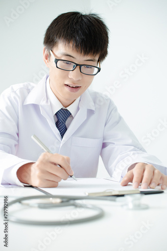 Close-up Of Male Doctor Filling The Medical Form