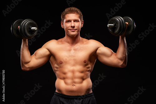 Smiling powerful shirtless muscular sportsman pumping biceps