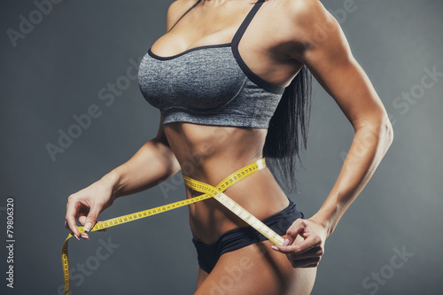 Woman measuring her waist with a yellow tape