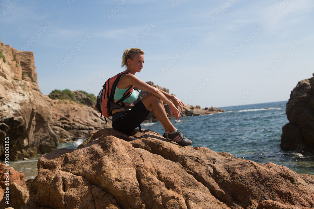 Climber girl sitting on a cliff with ocean in the background Climber girl sitting on a cliff with ocean in the background