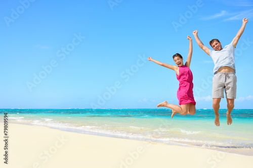 Beach vacation - happy fun tourists couple jumping
