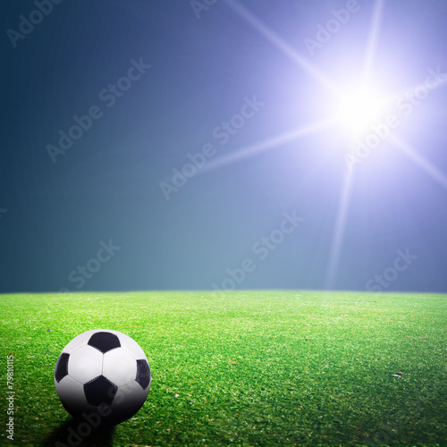 Shiny soccer ball in full stadium lights at night