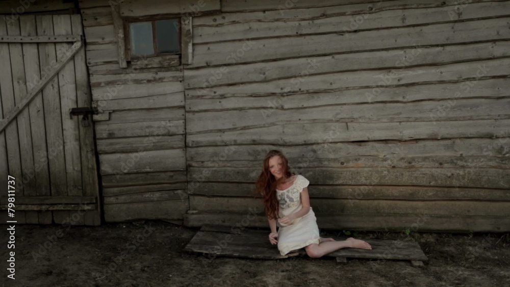 Girl with red hair posing near a wooden house Girl with red hair posing near a wooden house